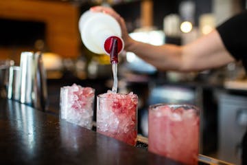 Nicole Vibar makes three Got Moxys with dragon berry Bacardi, lime juice, blackberry puree, cherry bitters spritz, and a lime at Moxy hotel bar in dow