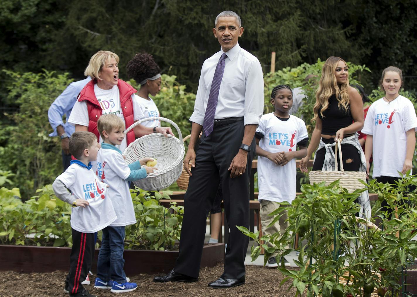 President Barack Obama, joins first lady Michelle Obama, children and participants during the harvest of the White House Kitchen Garden on the South Lawn in Washington, Thursday, Oct. 6, 2016. Carrying a basket at back right is singer Ashanti. (AP Photo/Manuel Balce Ceneta)