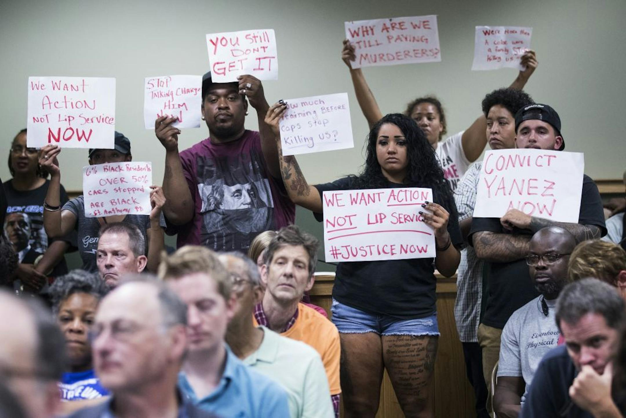 Protesters stood with signs Wednesday night during a Falcon Heights City Council workshop on the city's police contract with the St. Anthony department.