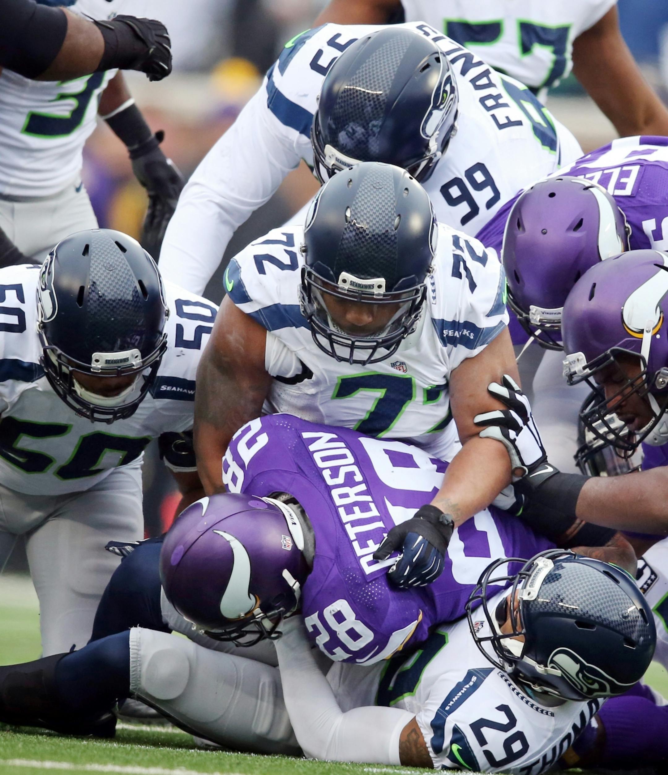 Minnesota Vikings running back Adrian Peterson (28) was stopped in the first quarter for no gain by Seattle Seahawks free safety Earl Thomas (29) and defensive end Michael Bennett (72) Sunday December 6, 2015 in Minneapolis, MN.