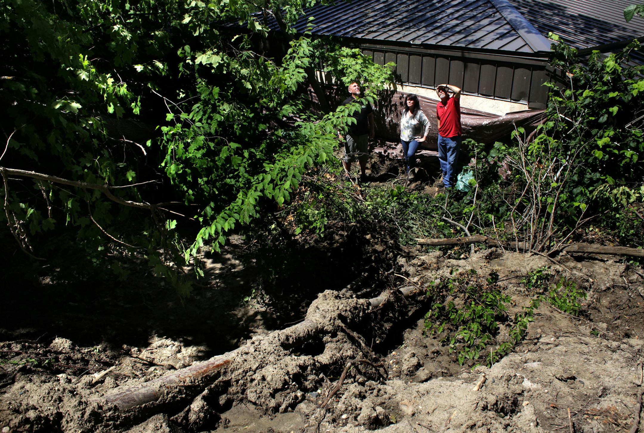 Tim Roets, Barbara Lee, and Kevin Breeggemann behind the brewery after a mudslide pushed 200 tons of debris down the hill.