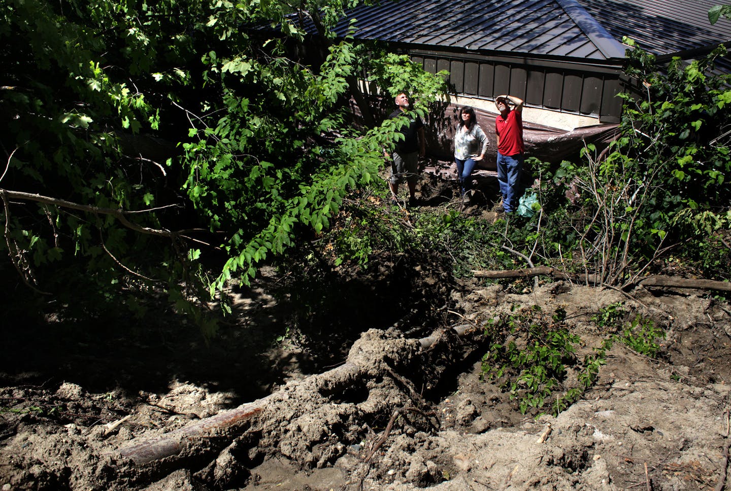 Tim Roets, Barbara Lee, and Kevin Breeggemann behind the brewery after a mudslide pushed 200 tons of debris down the hill.