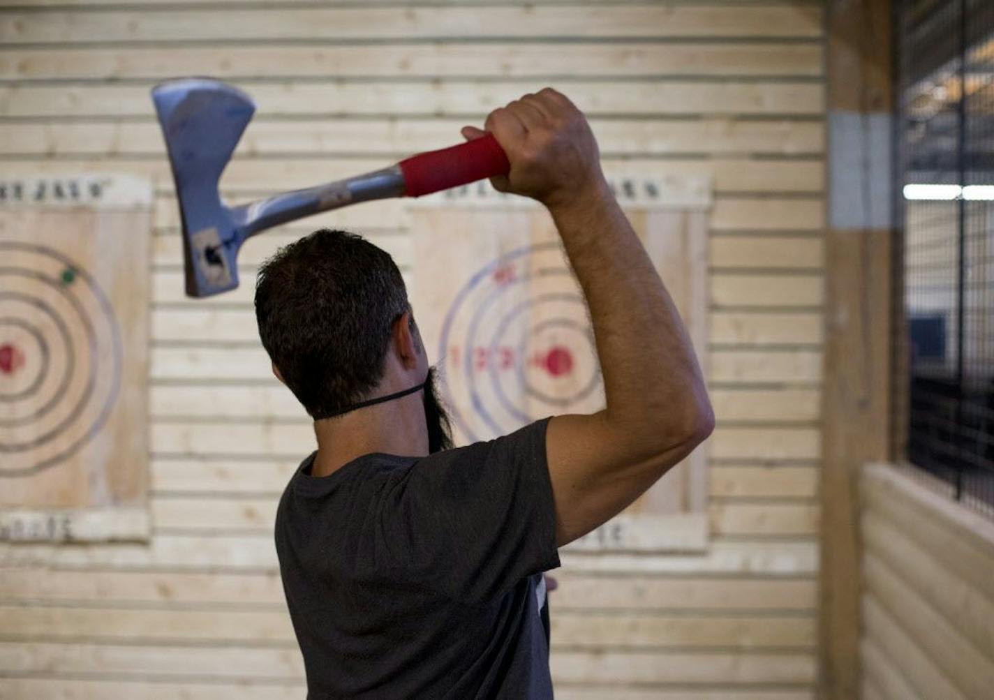 Jason Kimmel cocks his arm back to throw an axe at FlannelJax's Axe Throwing in St. Paul.