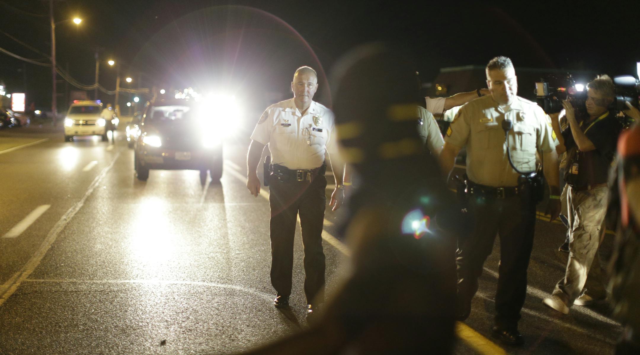 Police walk in the street during demonstrations in Ferguson, Mo., Aug. 11, 2015. Protests continued in Ferguson Tuesday night, two nights after bursts of gunfire had led to fears of renewed unrest. Police released surveillance video that they say shows an 18-year-old man who was shot by their officers pulling a gun out of his waistband and pointing it. (Whitney Curtis/The New York Times)