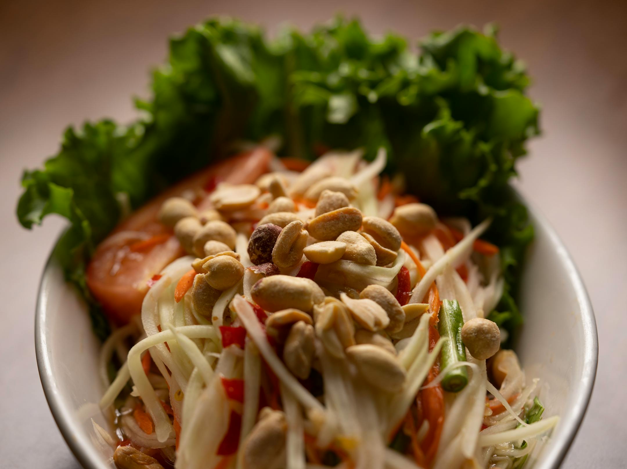 Thai papaya salad made with green papaya, carrots, tomatoes, long beans, peanuts, chili, fish sauce, and garlic.