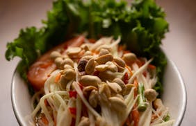 Thai papaya salad made with green papaya, carrots, tomatoes, long beans, peanuts, chili, fish sauce, and garlic.