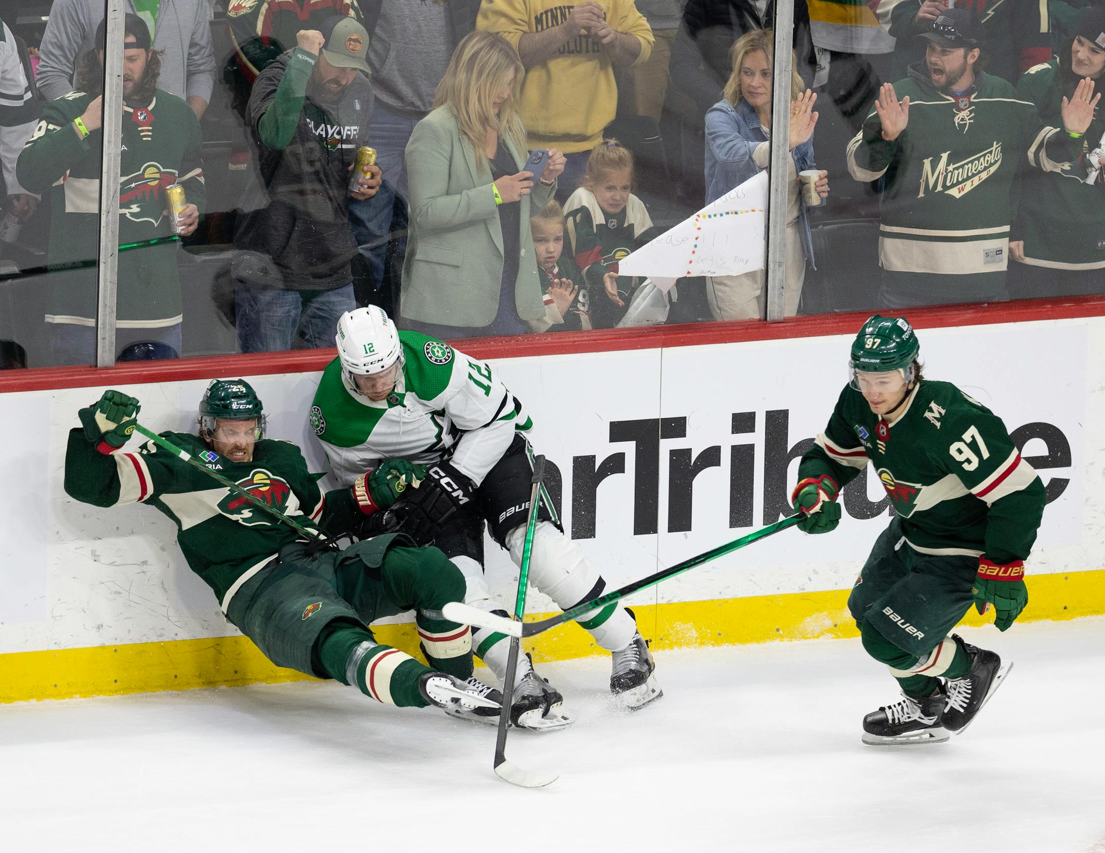 Minnesota Wild defenseman Jonas Brodin (25) falls to the ice after a check by Dallas Stars center Radek Faksa (12) as Wild left wing Kirill Kaprizov (97) skates past in the third period.