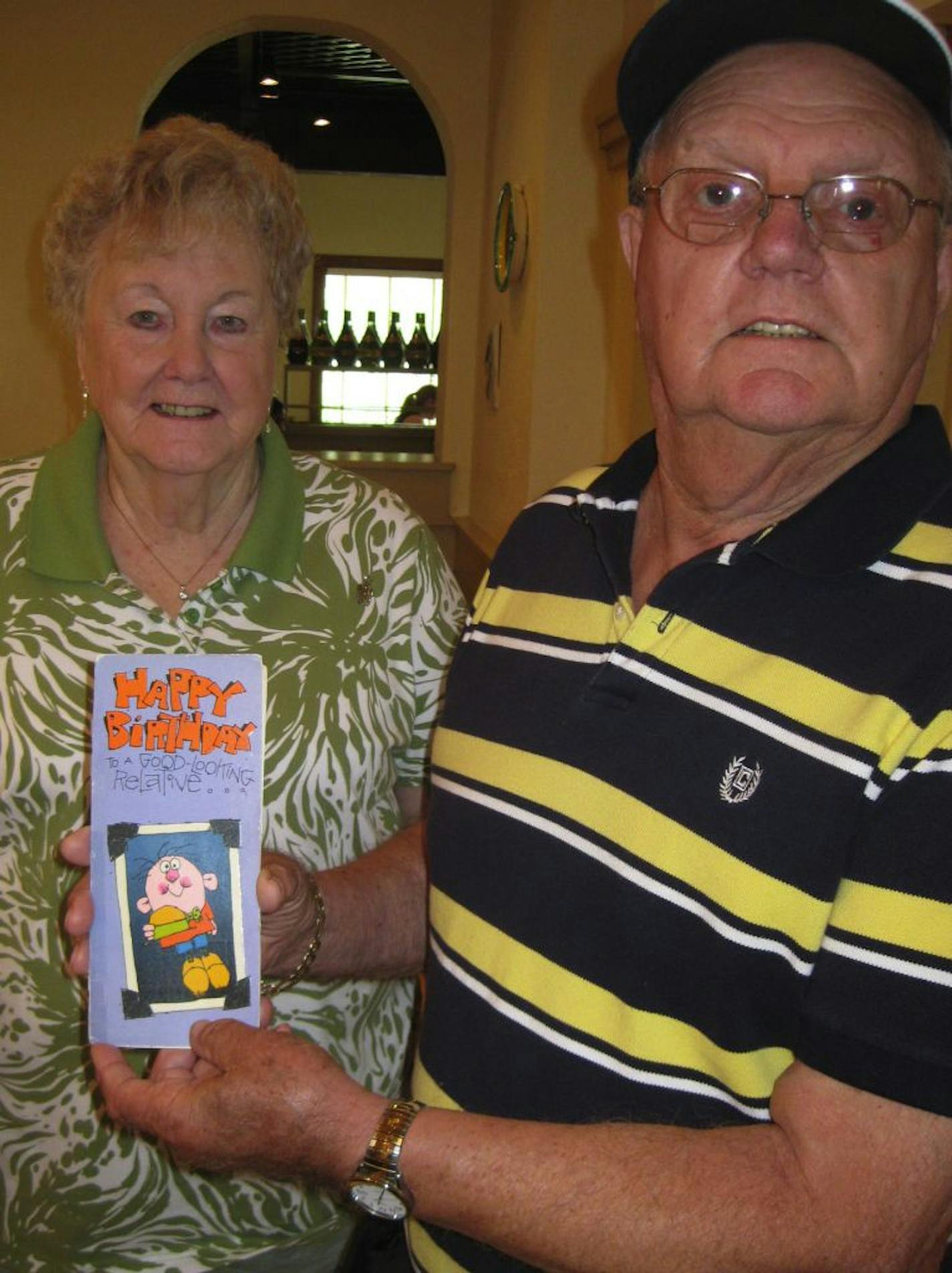 PHOTO BY GAIL ROSENBLUM. Tom Hamilton of Mora, Minnesota, (with wife, Gwen), turns 80 on Tuesday, June 7. He holds the birthday card that he and his sister-in-law, Madolyn Mann, 79, of Pharr, Texas, have exchanged annually since 1975.