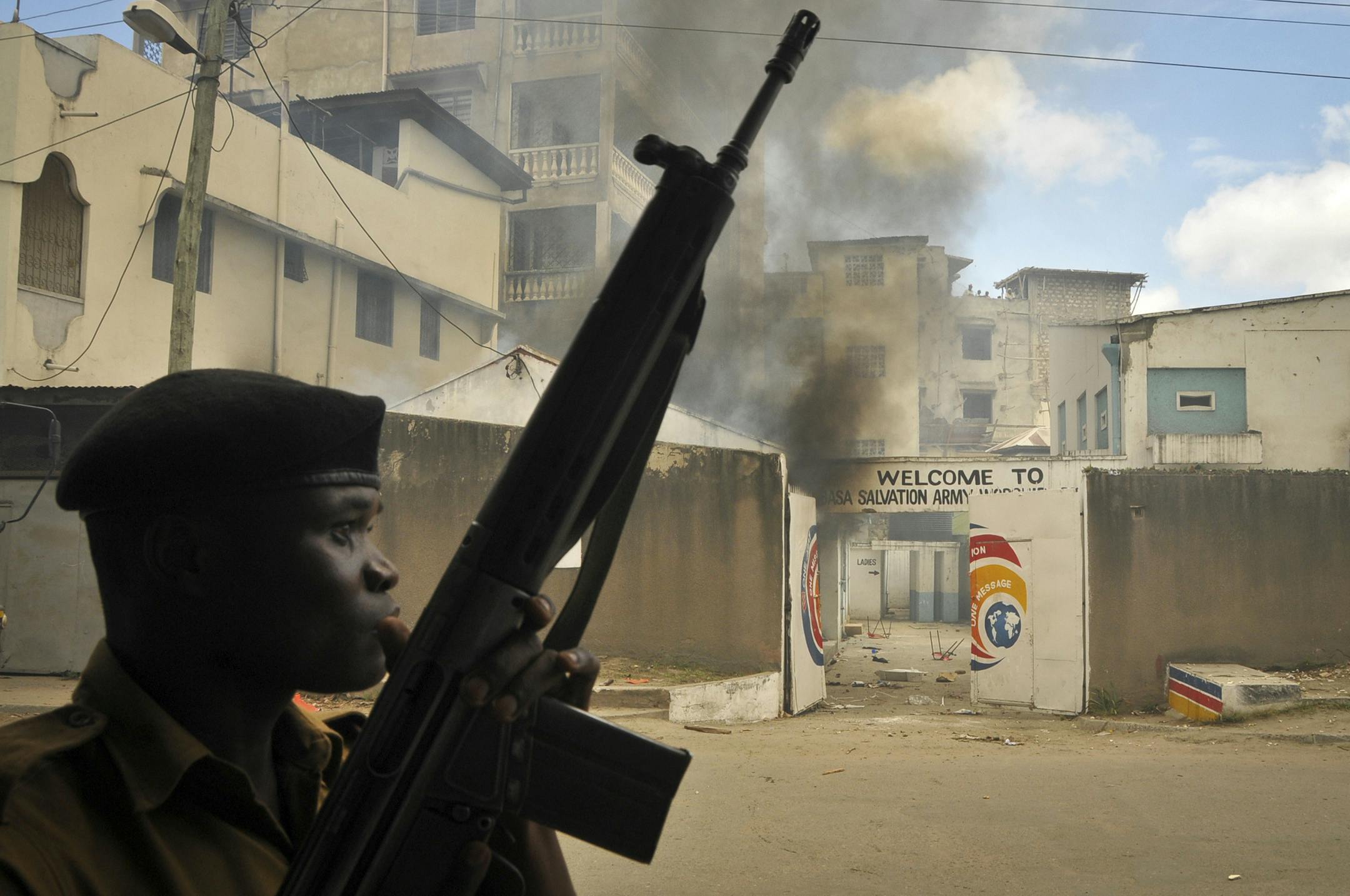 An armed police officer stands guard in front of the Salvation Army Church after it was set on fire by rioting youths, following Friday Muslim prayers in Mombasa, Kenya, Friday, Oct. 4, 2013. A religious leader on Kenya's coast says that the Muslim cleric Sheikh Ibrahim Ismael who preached at Mombasa's Masjid Musa Mosque, whose previous imam Aboud Rogo Mohammed was mysteriously shot dead in August 2012, has died in a barrage of bullets late Thursday near the coastal city of Mombasa. (AP Photo)