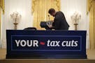 FILE -- A White House staff member attaches the presidential seal marker to a podium ahead of President Donald Trump's remarks celebrating the Tax Cut