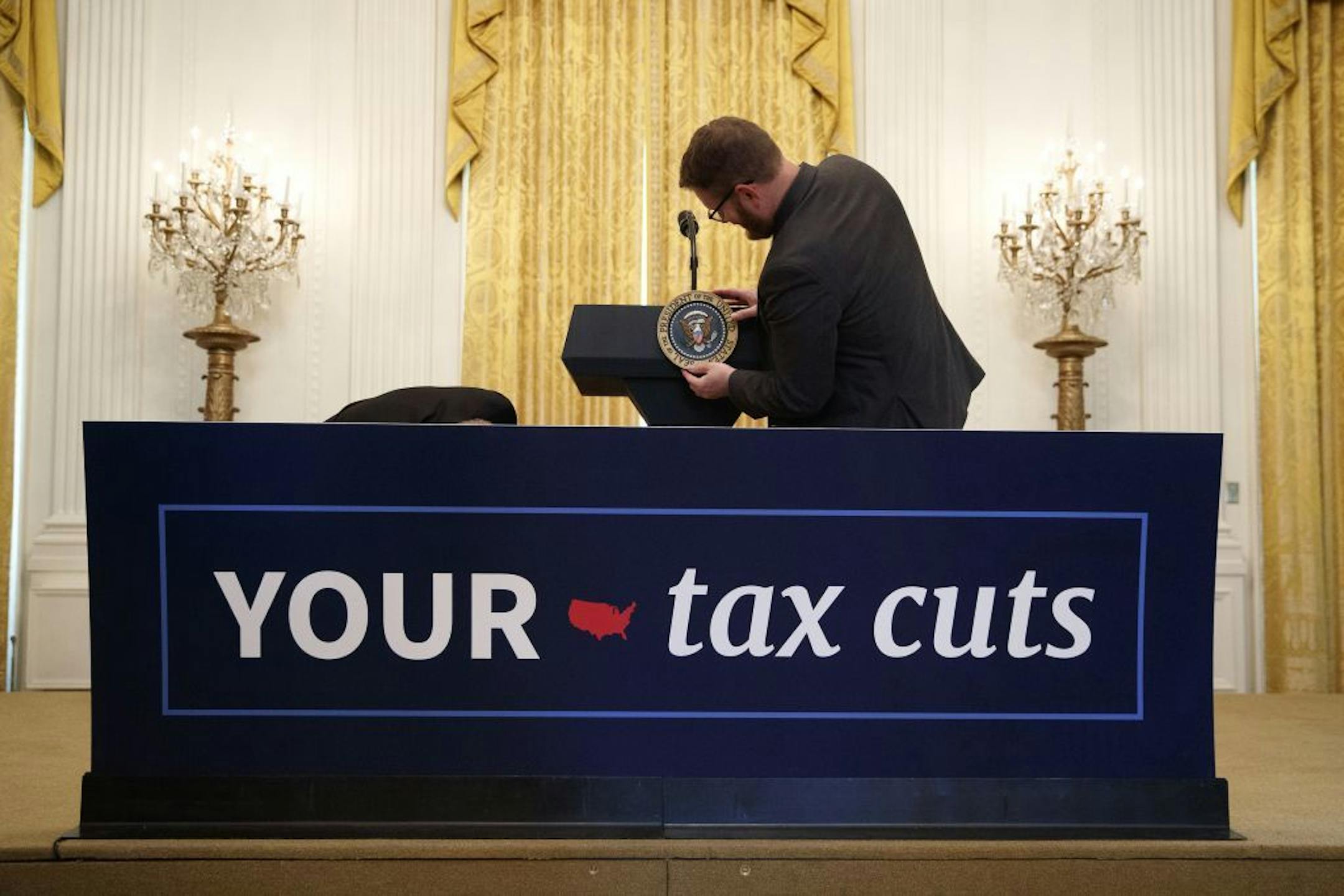 FILE -- A White House staff member attaches the presidential seal marker to a podium ahead of President Donald Trump's remarks celebrating the Tax Cuts and Jobs Act, at the East Room of the White House, in Washington, D.C., on June 29, 2018. American companies could potentially authorize the repurchase of $1 trillion in stock by the end of 2018. (Tom Brenner/The New York Times) -- PART OF A COLLECTION OF STAND-ALONE PHOTOS FOR USE AS DESIRED IN YEAREND STORIES AND RECAPS OF 2018 --