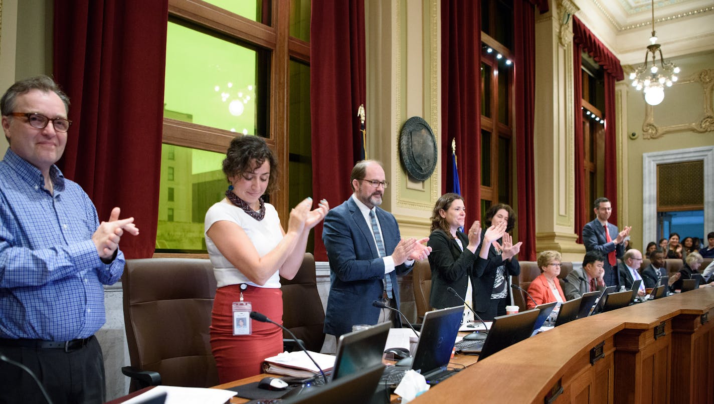 Some Minneapolis City Council members stood to applaud after the council unanimously approved an ordinance that will require most city businesses to provide paid sick leave to workers, Friday, May 27, 2016, in Minneapolis. (Glen Stubbe/Star Tribune via AP) MANDATORY CREDIT; ST. PAUL PIONEER PRESS OUT; MAGS OUT; TWIN CITIES LOCAL TELEVISION OUT