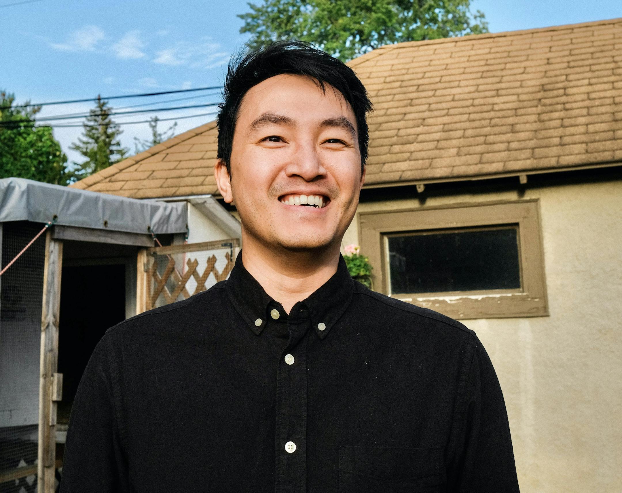 photo depicts author Trung Le Nguyen, standing in front of a house wearing a black shirt