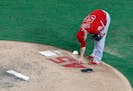 Angels starting pitcher Trevor Cahill reaches down to touch the number 45 on the back of the mound as he prepares to work against the Texas Rangers. T
