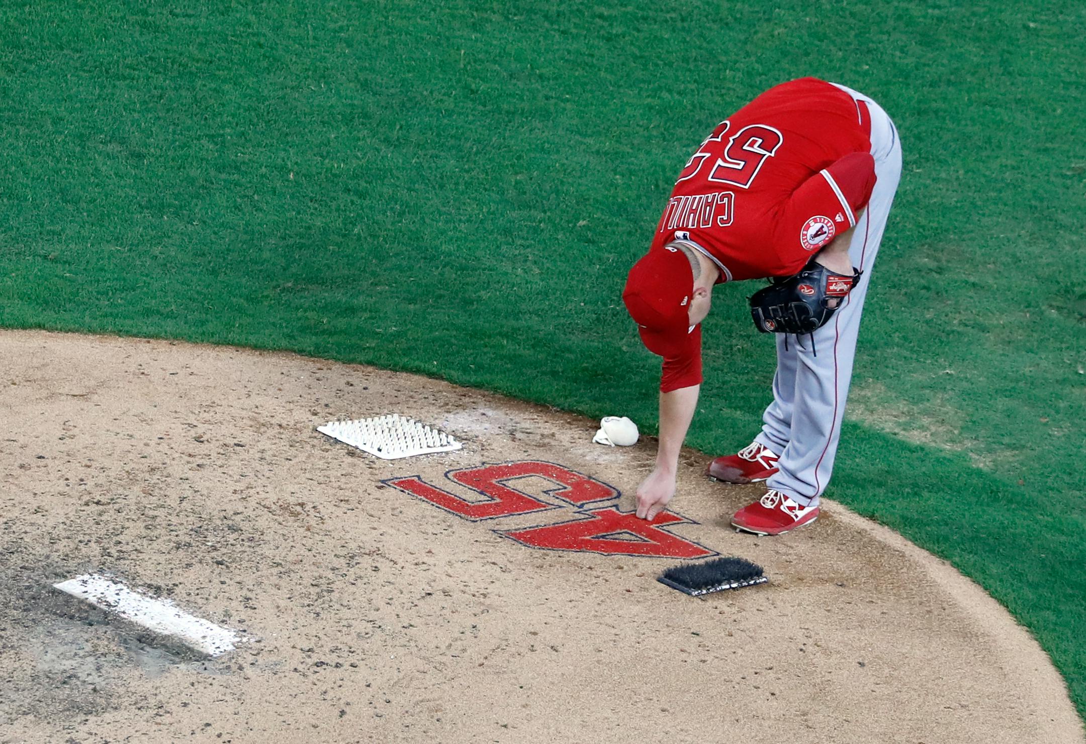 Angels starting pitcher Trevor Cahill reaches down to touch the number 45 on the back of the mound as he prepares to work against the Texas Rangers. The number honors Tyler Skaggs