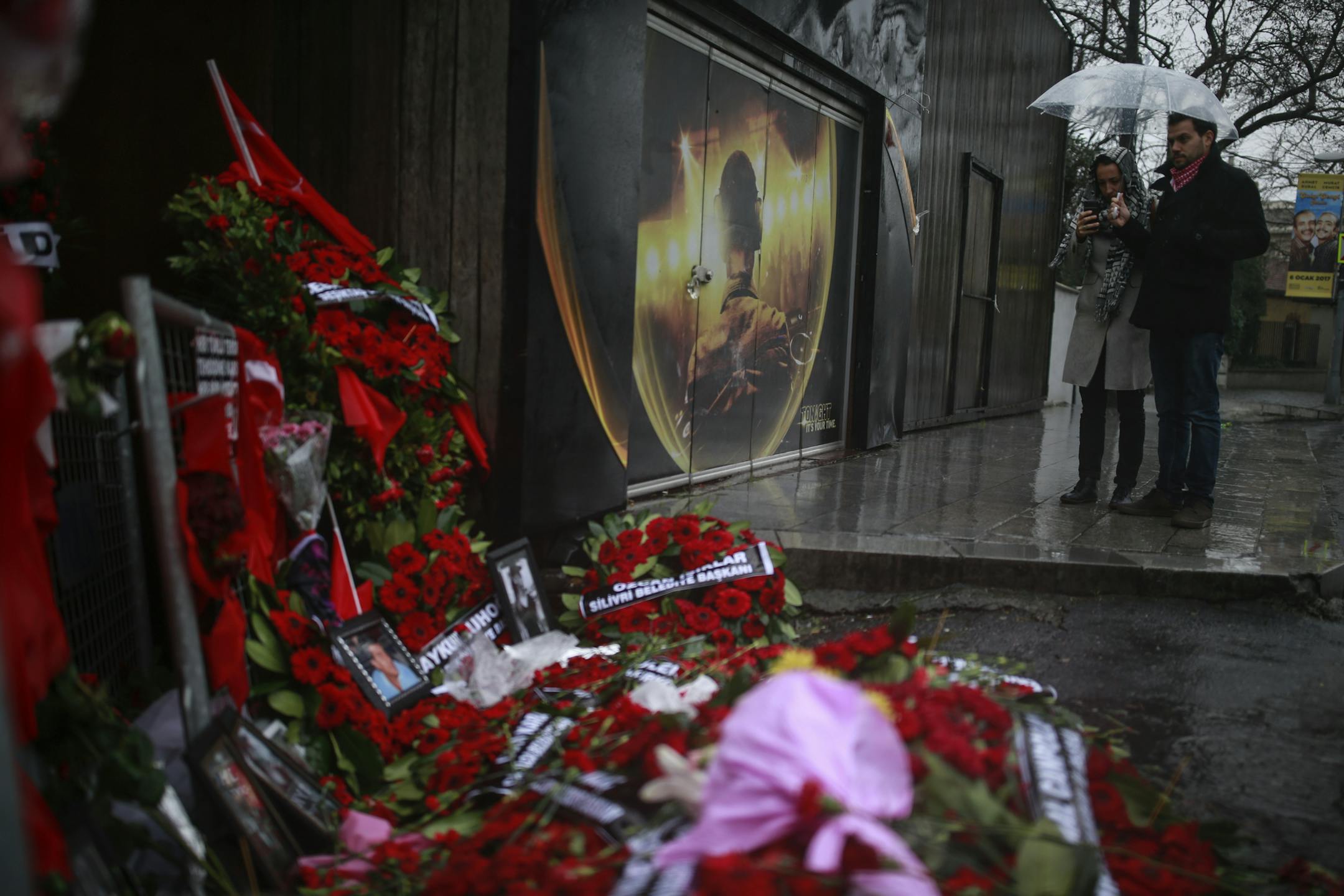 People look at floral tributes left outside the nightclub for the victims of the gunman attack, in Istanbul, Thursday, Jan. 5, 2017. Police on Thursday conducted more raids in their hunt for the gunman that killed 39 people at an Istanbul nightclub, detaining several people at a housing complex in the city's outskirts, the state-run news agency reported. (AP Photo/Emrah Gurel) ORG XMIT: XLP802