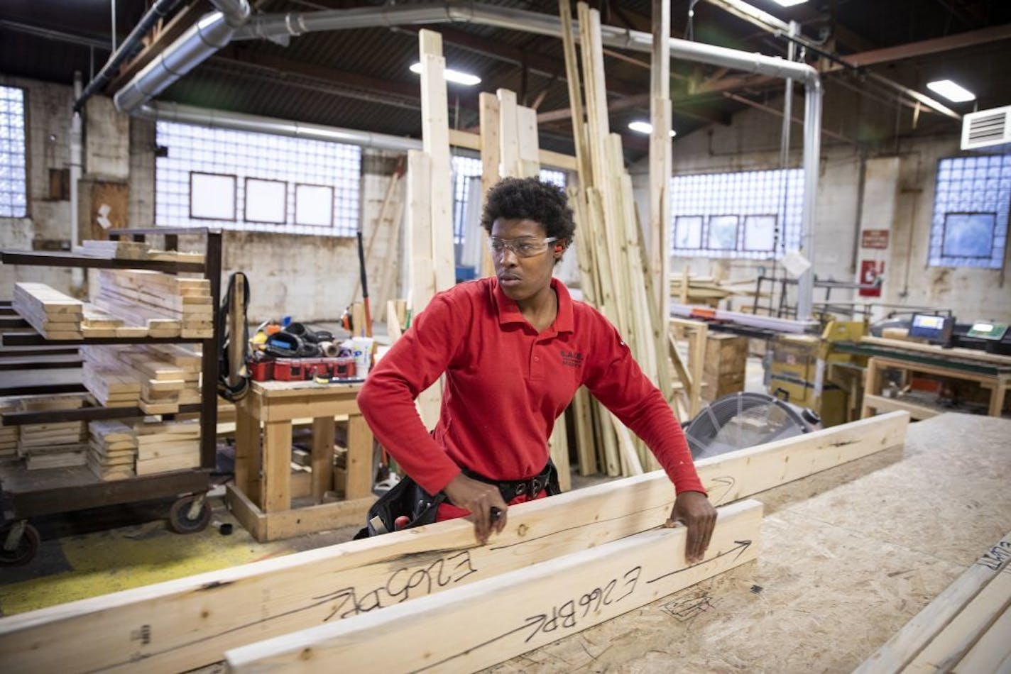 Valencia Hardy cuts and marks pieces of wood for wall panels.