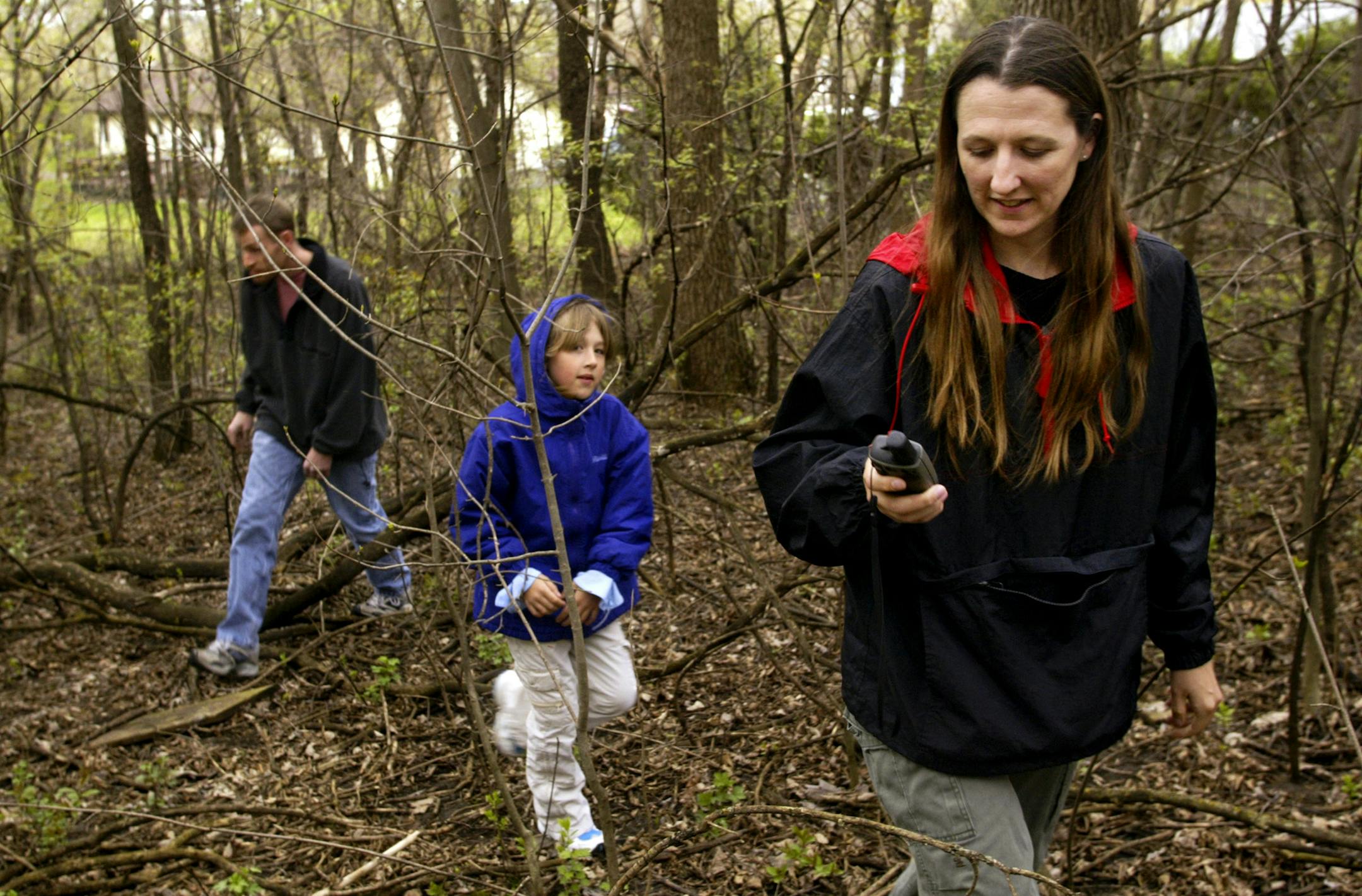 From right, Julie Lindquist, her eight-year-old daughter, Mikayla, and husband, Mike, search for a geocache in the woods at Longridge Park in Apple Valley using their GPS Wednesday, April 19, 2006. The Lindquist's will be competing in the South of the River Recreators' "Amazing GPS Family Race" Saturday, April 29, 2006. Jeffrey Thompson &#xd4; jthompson@startribune.com GENERAL INFORMATION: Preview of the South of the River Recreators' "Amazing GPS Family Race," scheduled for April 29th. This is