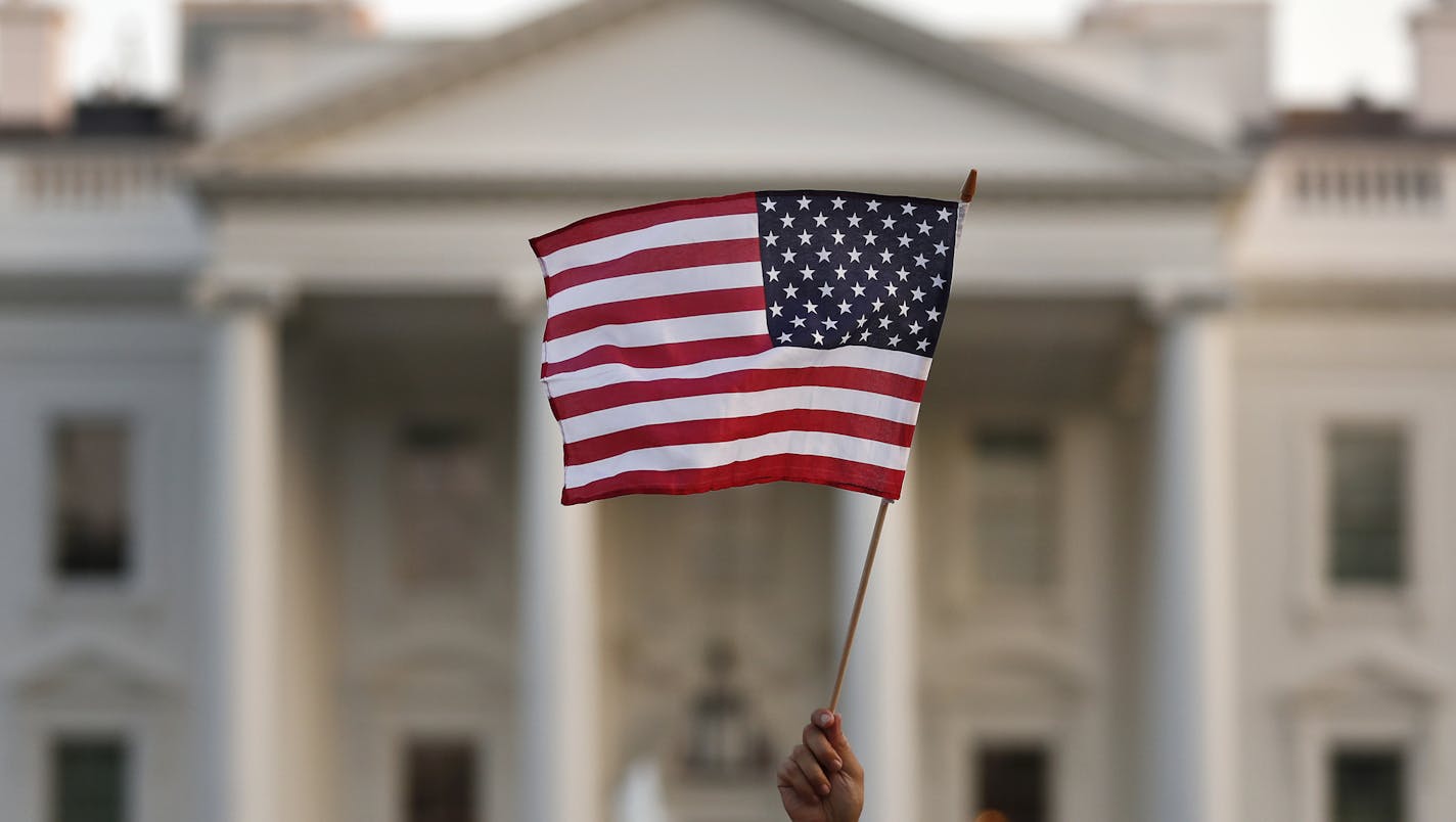 FILE - In this Sept. 5, 2017, file photo, a flag is waved outside the White House, in Washington. The Trump administration is extending a ban on green cards issued outside the United States until the end of 202 and adding many temporary work visas to the freeze, including those used heavily by technology companies and multinational corporations. (AP Photo/Carolyn Kaster, File)