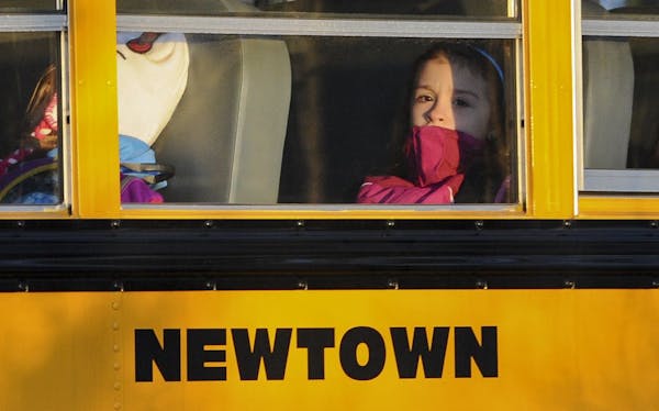 A girl sits on a Newtown bus leaving the new Sandy Hook Elementary School after the first day of classes in Monroe, Conn., Thursday, Jan. 3, 2013.