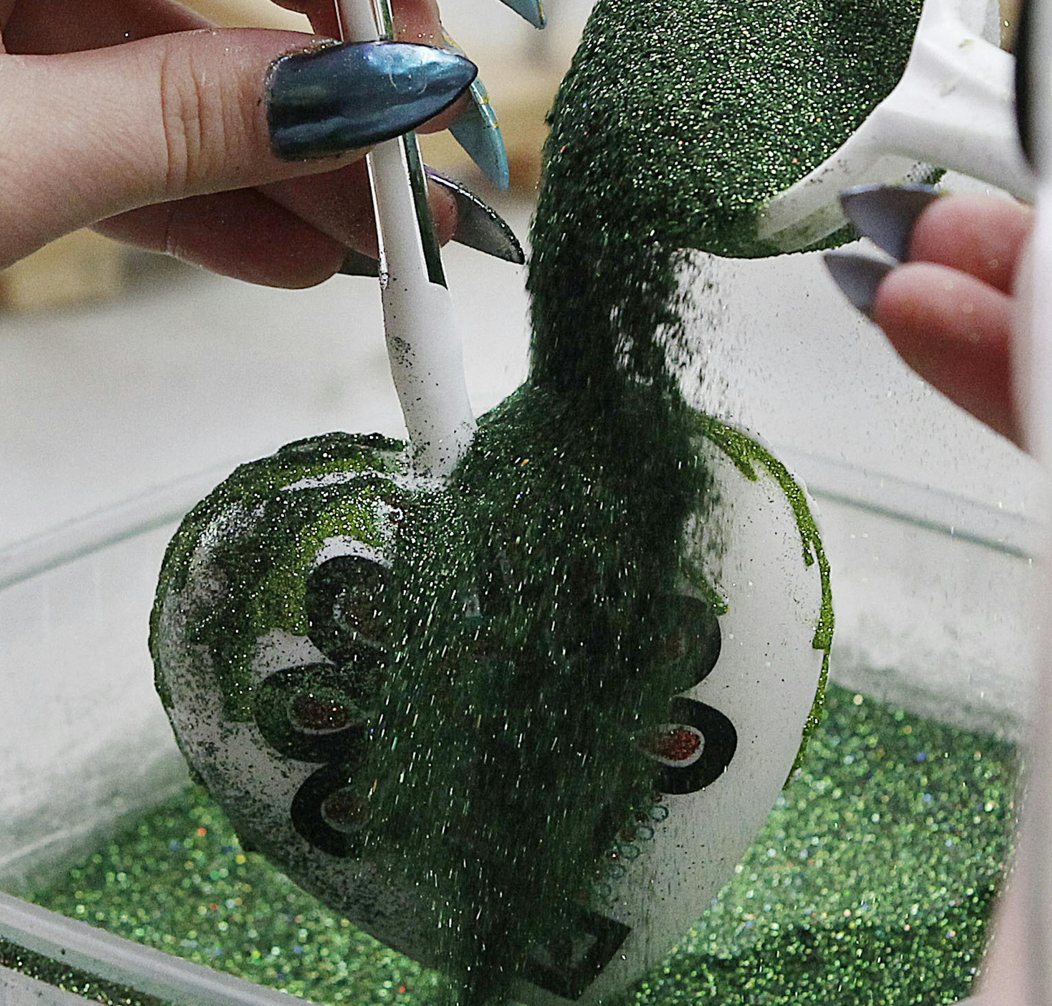 In this Nov. 28, 2017 photo a painter decorates blown-glass Christmas tree ornaments with glitter at the Silverado manufacture in Jozefow, near Warsaw, Poland. The manufacture sells about one million decorations a year, primarily to the U.S. and Europe. They can be found at the White House. (AP Photo/Czarek Sokolowski) ORG XMIT: XVS214