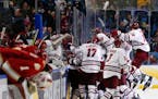 Massachusetts players celebrate a 4-3 overtime victory over Denver in the semifinals of the Frozen Four NCAA men's college hockey tournament Thursday,