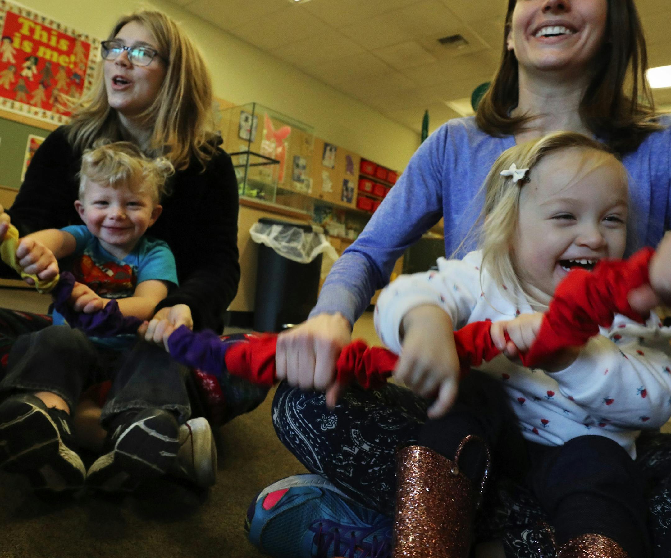 Dylan, on Chelsea May's lap, left, and Raisa, with Sonia Sleiman, use a stretchy band during a Childhaven music therapy class. It's fun, it's exercise and for many at Childhaven it's their favorite time of the week plus it helps with motor skills. (Alan Berner/Seattle Times/TNS) ORG XMIT: 1258891
