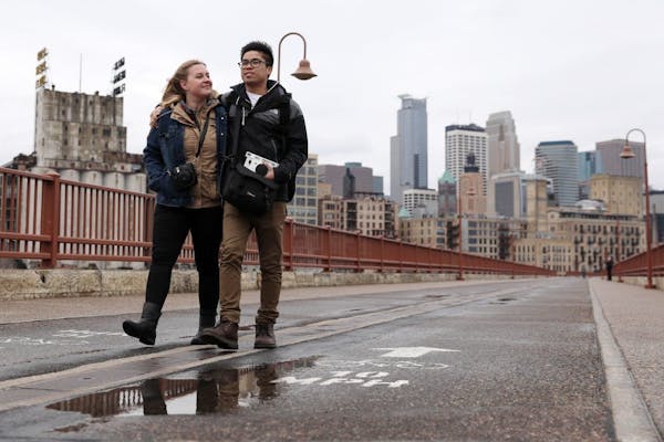 Ellie Drews and her boyfriend Clarence Insixiengmay walked down the Stone Arch Bridge as heavy storm clouds loomed over downtown Minneapolis ahead of 