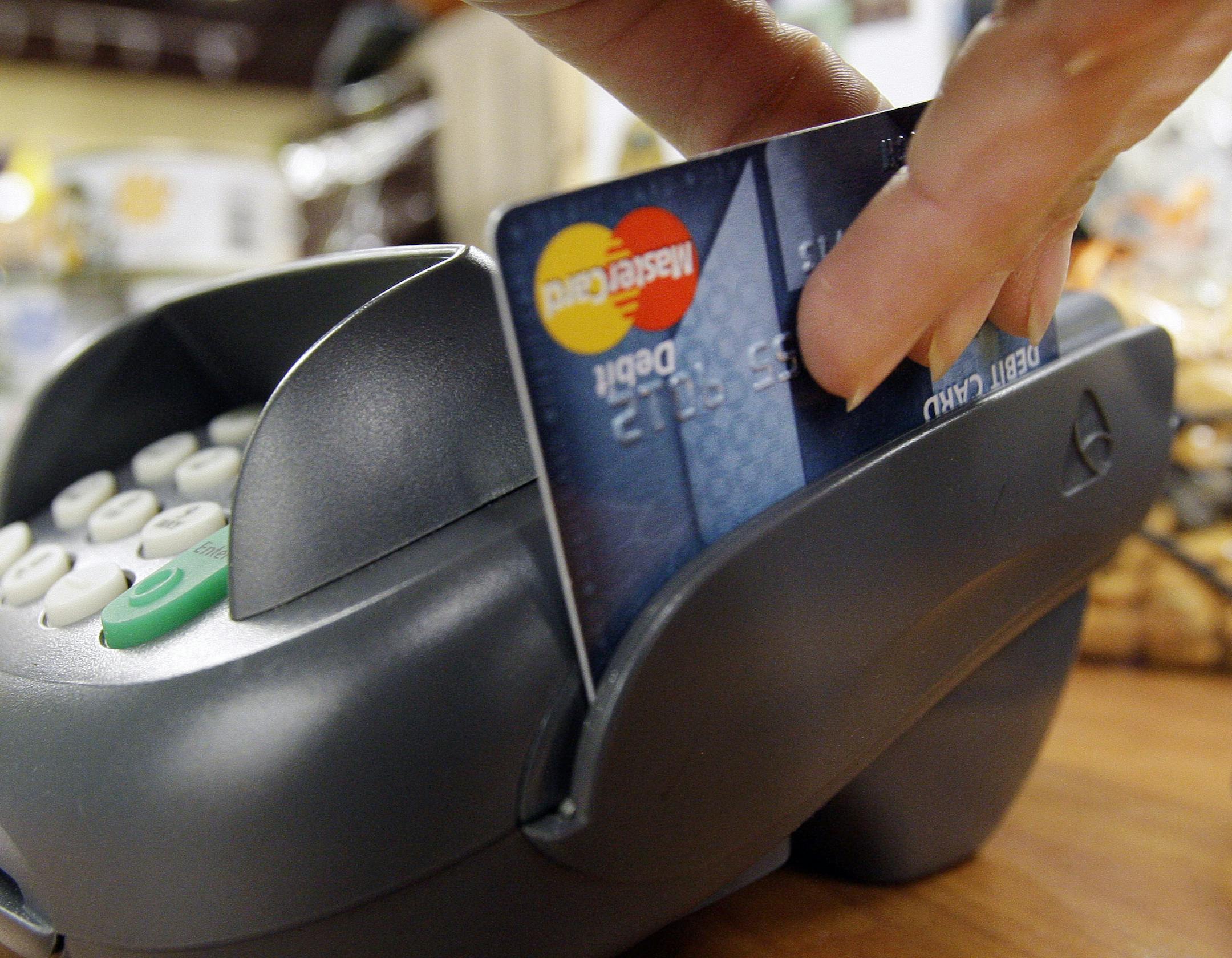 FILE - In this Nov. 2, 2009 file photo, a customer swipes a MasterCard debit card through a machine while checking-out at a shop in Seattle. For many, part of the strategy for keeping on budget includes a plan to leave the credit cards at home and use a debit card at the checkout. (AP Photo/Elaine Thompson, file)