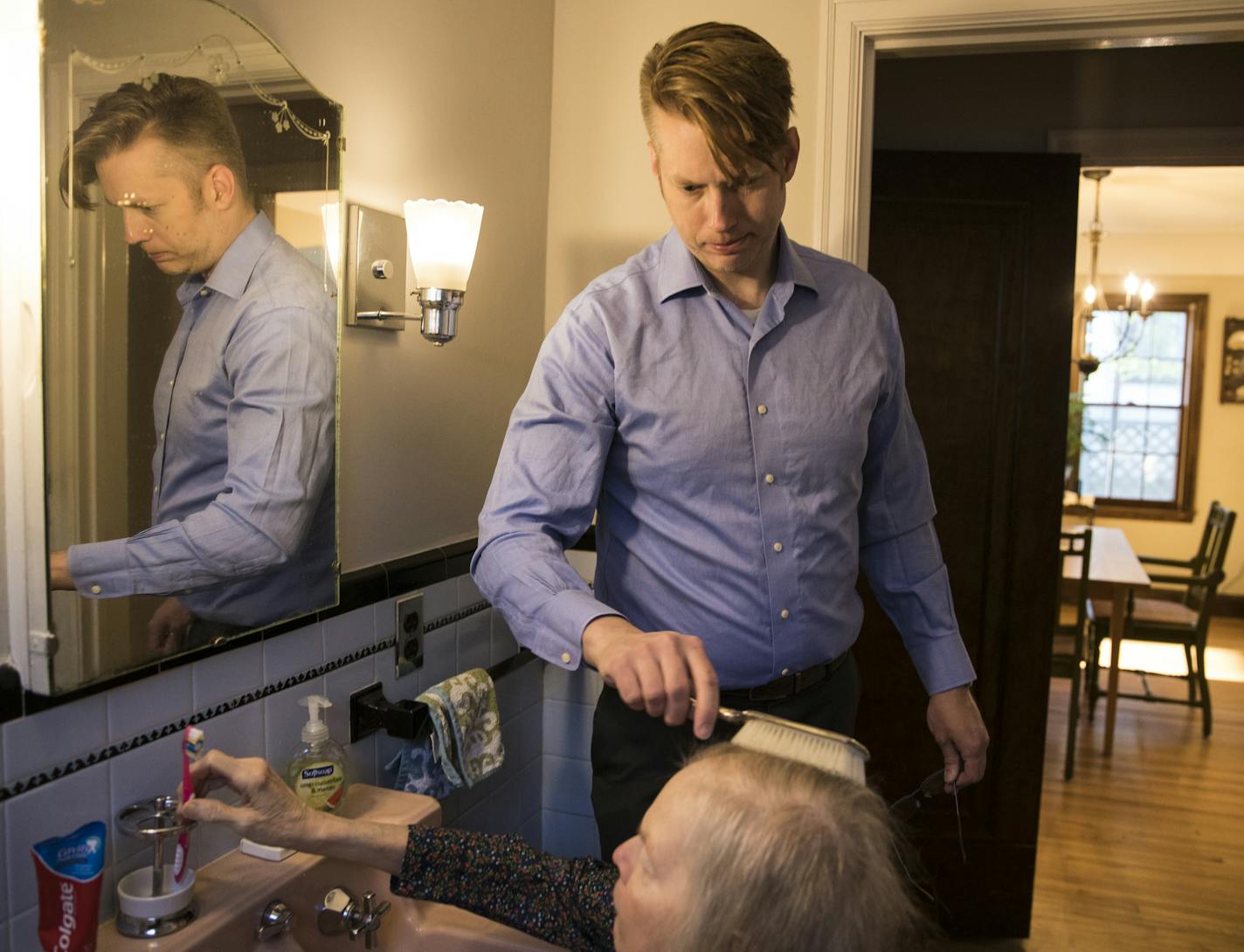 Christian Fritzberg brushed his mother Barbara Fritzberg's hair in the bathroom before he bringing her to an adult day care center on April 21, 2017 in Minneapolis, Minn. Barbara has Parkinson's disease and need help with daily activities so her son bought the home next to his to be able to care for her and give her her own space. ] RENEE JONES SCHNEIDER &#x2022; renee.jones@startribune.com