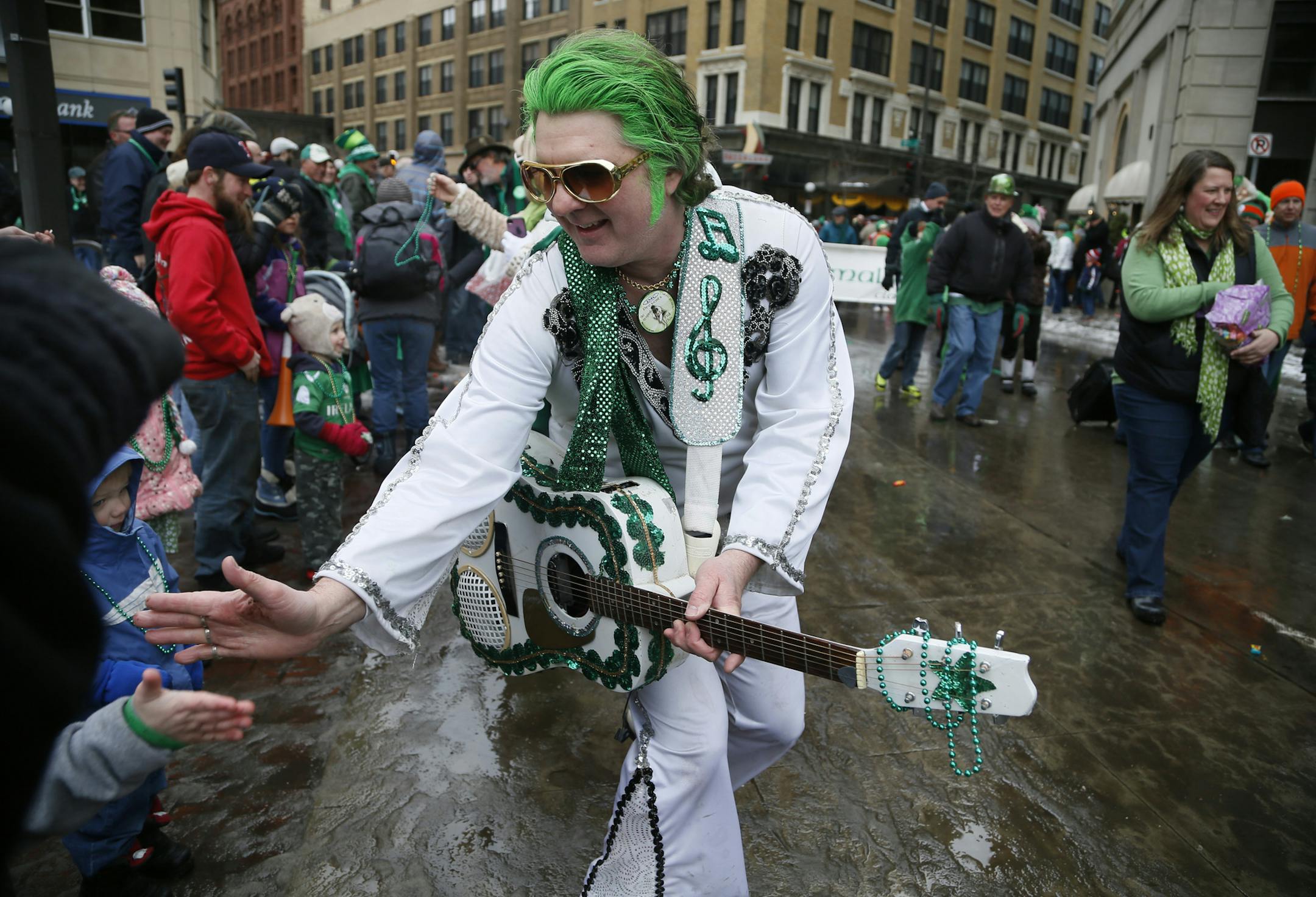 Robert Klick dressed as a green Elvis gave fans high fives during the 48th annual St. Patrick's day parade Monday March 17, 2014 in St. Paul, MN. ] JERRY HOLT jerry.holt@startribune.com