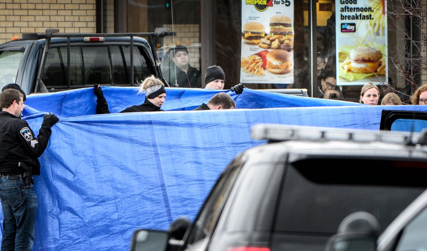 Burnsville Police held a tarp around the body as BCA investigators and Medical Examiners investigated a shooting that occured in a McDonald's parking lot Thursday morning involving a Burnsville police officer. ] GLEN STUBBE * gstubbe@startribune.com Thursday March 17, 2016 EDS, graphic content, covered body of victim in parking lot