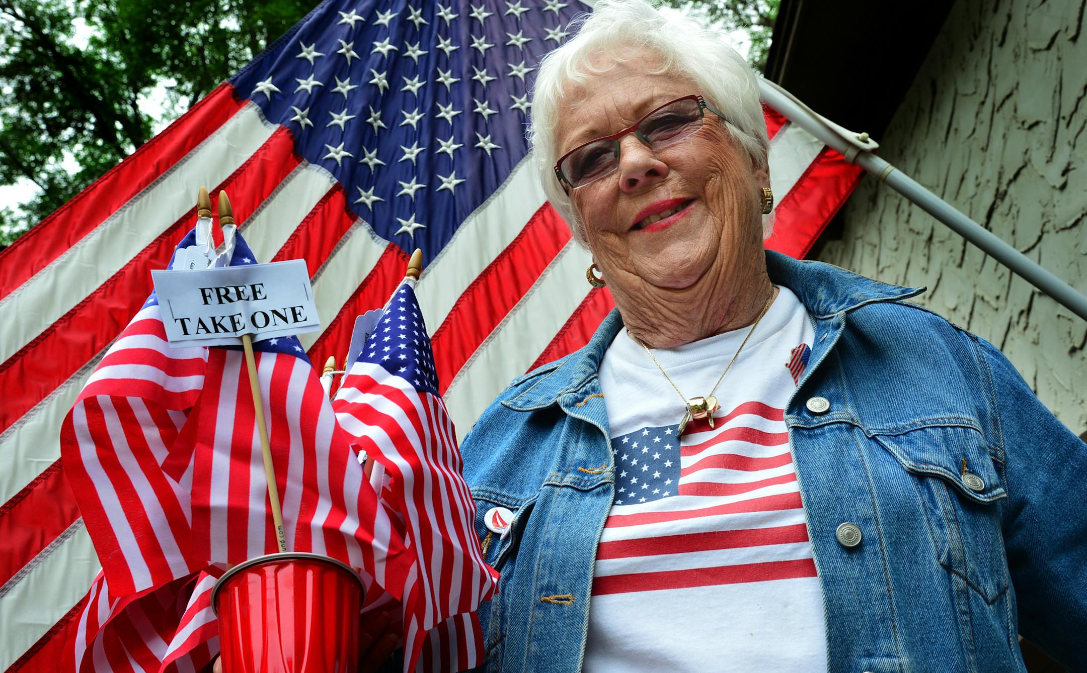 Martie McGlasson of Tonka Bay leaves her house to go door-to-door fundraising for Lake Minnetonka's annual Fourth of July celebration. Carrying a bucket of flags, McGlasson is going around asking residents to help support the largely free event that is mostly supported by donations. When she can't speak directly to residents she will leave a flag with donation information on a tag. ]Richard.Sennott@startribune.com Richard Sennott/Star Tribune Tonka Bay Minn.Wednesday 6/25/2014) ** (cq)