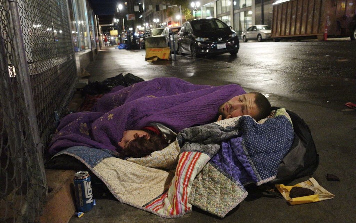 In this Sept. 18, 2017 photo, Taz Harrington, right, sleeps with his girlfriend, Melissa Ann Whitehead, on a street in downtown Portland, Ore. Harrington, who is in his 20s, said he met Whitehead, who was already homeless, online and came to Oregon to be with her even though he knew they would be sleeping outside. He said although he was hoping to find work, his girlfriend becomes anxious when he's away, so he stays with her most of the time.