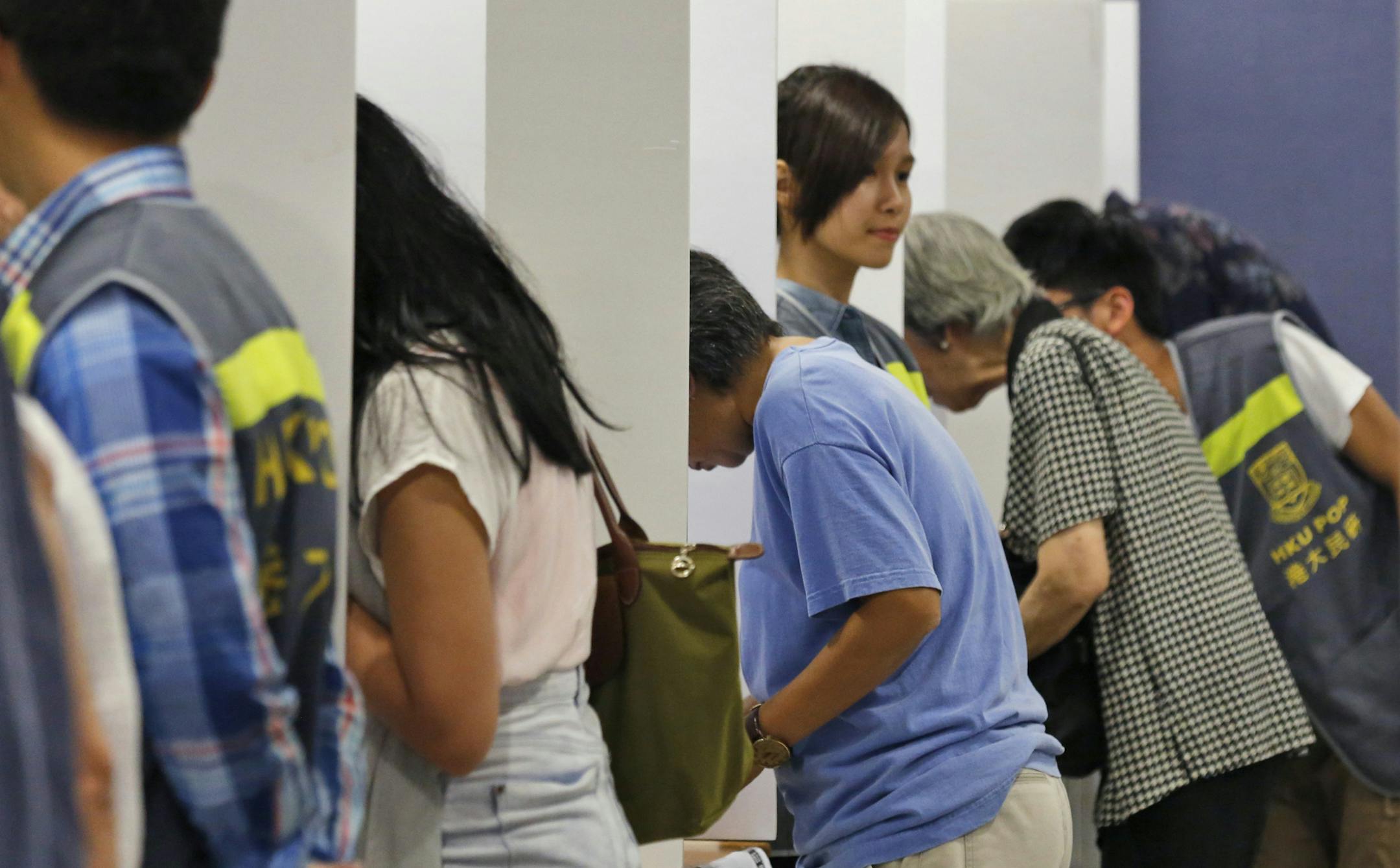 People vote in a polling station for an unofficial referendum on democratic reform in Hong Kong Sunday, June 22, 2014. More than half a million Hong Kongers have voted in an unofficial referendum on democratic reform in the specially administered Chinese city that Beijing has blasted as illegal. (AP Photo/Kin Cheung)