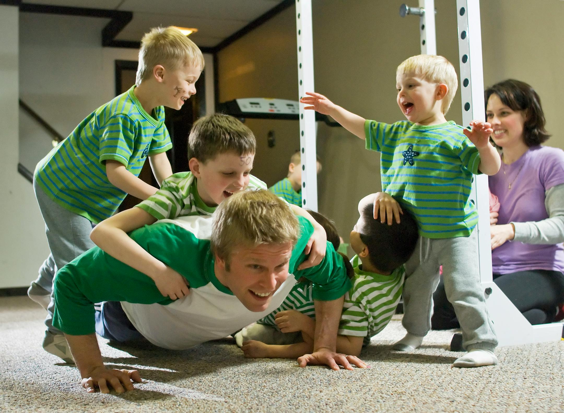 Downstairs in the Otis family workout room, Sheff Otis demonstrates how he uses his kids as "live" weights during his workout. Seen here doing push-ups with a few added pounds on his back. Left to right, Michael, 4; James, 7; Sheff, John , 5; Mark, 2 and mom, Deirdre.
