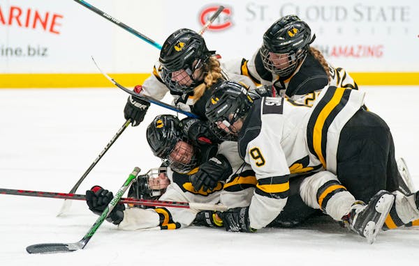 Warroad forward Kate Johnson (16) is swarmed by teammates after she scores her team's third goal against Proctor/Hermantown in the second period of th