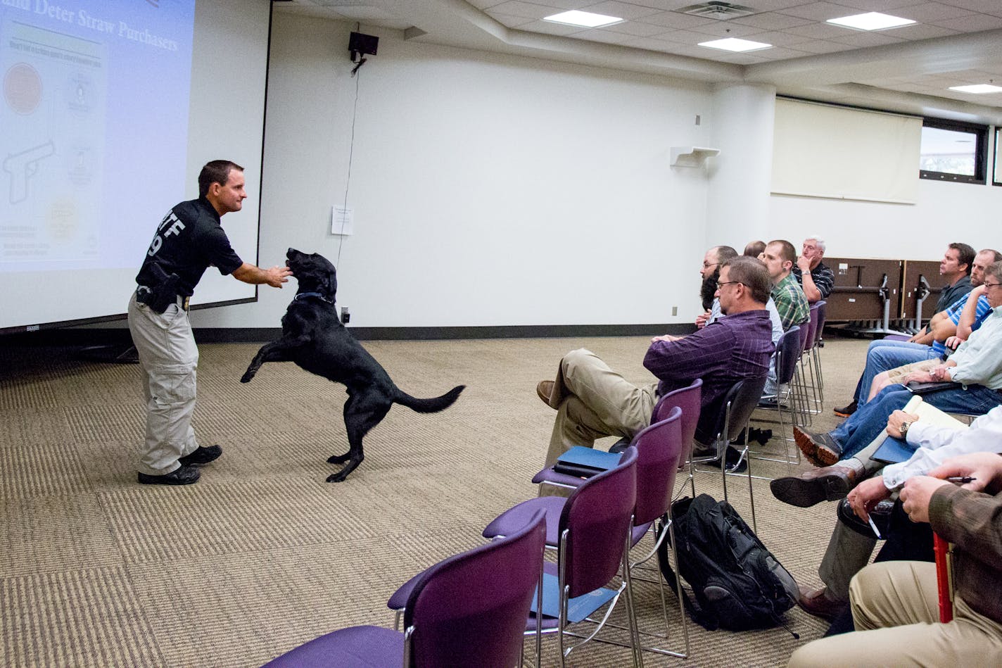 ATF Special Agent Nic Garlie speaks on straw purchasers during the Federal Firearms License Educational Seminar with explosive detection K9 Brock. ] COURTNEY PEDROZA &#xef; courtney.pedroza@startribune.com; Federal Firearms License Educational Seminar for gun store owners to protect against crimes like straw purchasing; Hennepin County Library in Edina; July 27, 2017; K9 Brock; explosive detection K9 including firearms, shell casing, and ammo