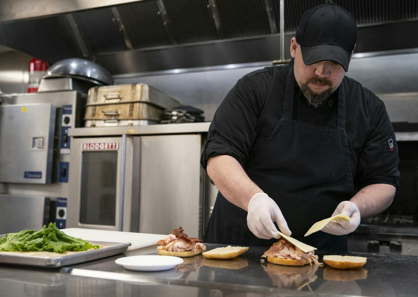 Kris Werbelow, kitchen manager at MidCoast Catering, prepared turkey and Swiss sandwiches on ciabatta bread on Tuesday morning. The sandwiches would later be delivered to BeeHive Homes Assisted Living. ]
ALEX KORMANN &#x2022; alex.kormann@startribune.com MidCoast Catering and Yellow Bike coffee shop banded together with a judge to raise $13,000 to deliver meals to healthcare workers. They also put together small packages of food and coffee to bring to local healthcare workers, including those th