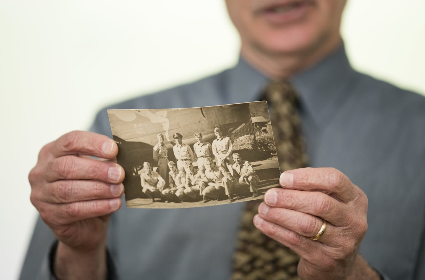 Dean Scheele holds a photo of his father's World War II bomber crew. His dad was the only crew member to survive the war.