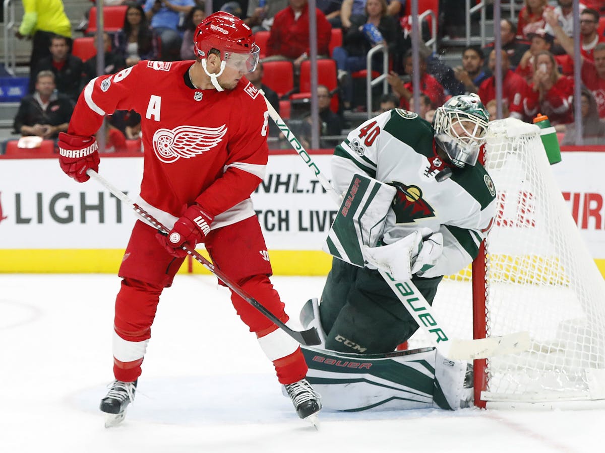Minnesota Wild goalie Devan Dubnyk (40) deflects the puck off his mask as Detroit Red Wings left wing Justin Abdelkader (8) looks on in the second per