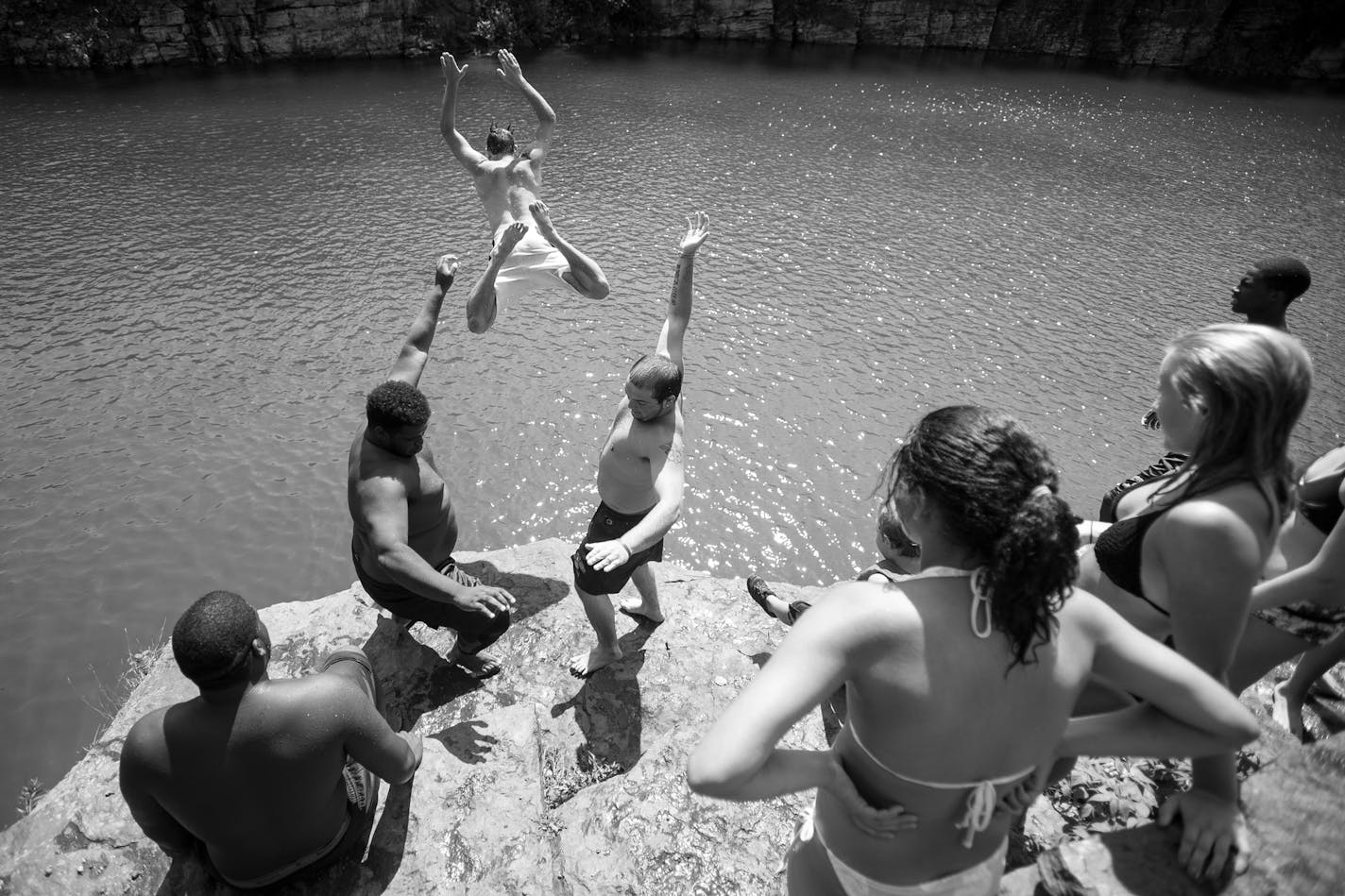 Surrounded by Eveleth, Gilbert and Virginia locals, linemen Uriah English, left, and Levi Ritacco tossed kicker Nolan Johnson into Lake Ore-be-gone during a cliff diving trip before practice in mid-August. ] Aaron Lavinsky &#x2022; aaron.lavinsky@startribune.com Photos to accompany a story on the Mesabi Range College Football team in Virginia, Minnesota. The team, which consists mostly of black athletes recruited from around the country, struggles to find its place in mostly-white mining country