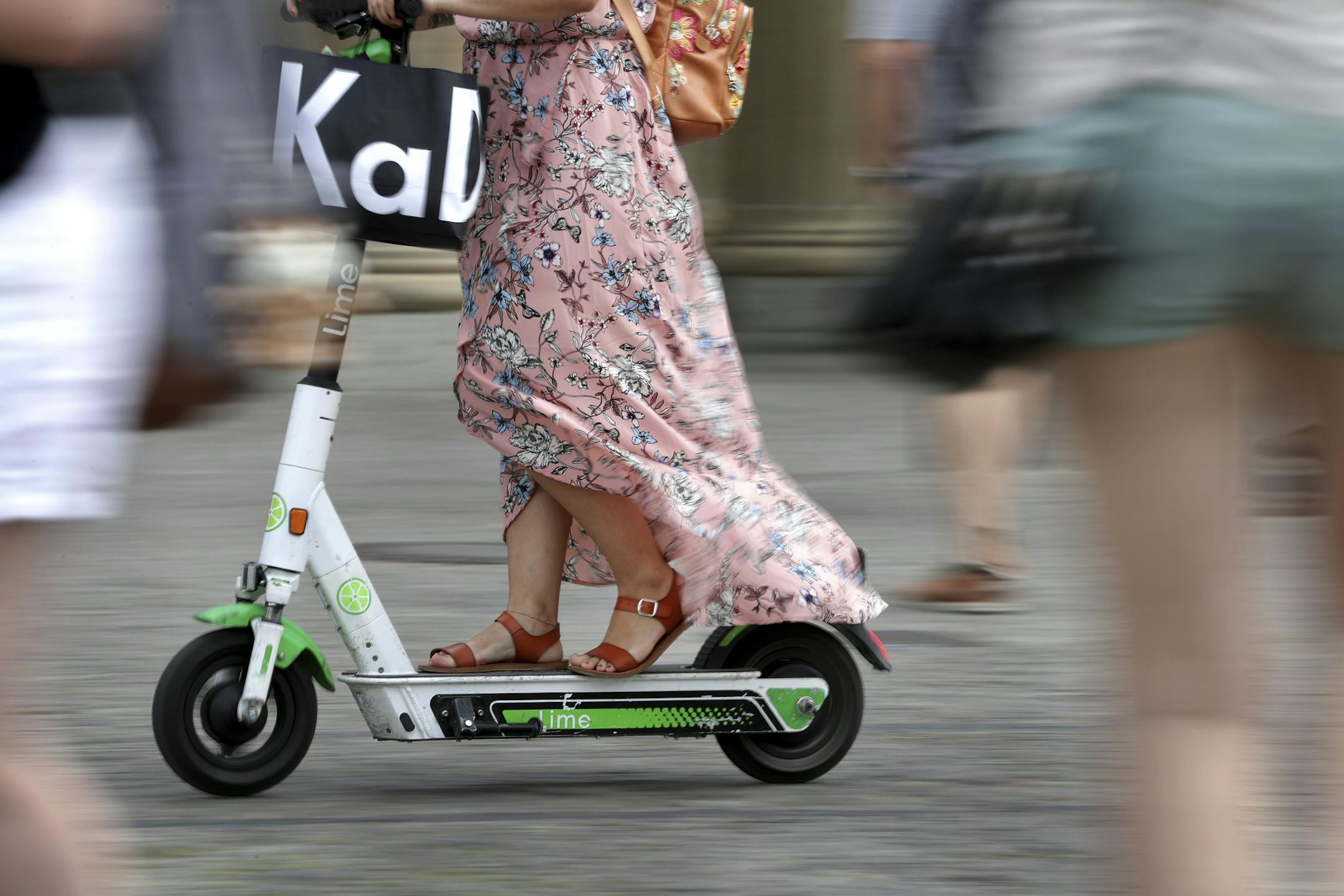 In this Tuesday, Aug. 6, 2019 photo a woman drives an electric scooter on a square in front of the Brandenburg Gate in Berlin, Germany. (AP Photo/Michael Sohn)