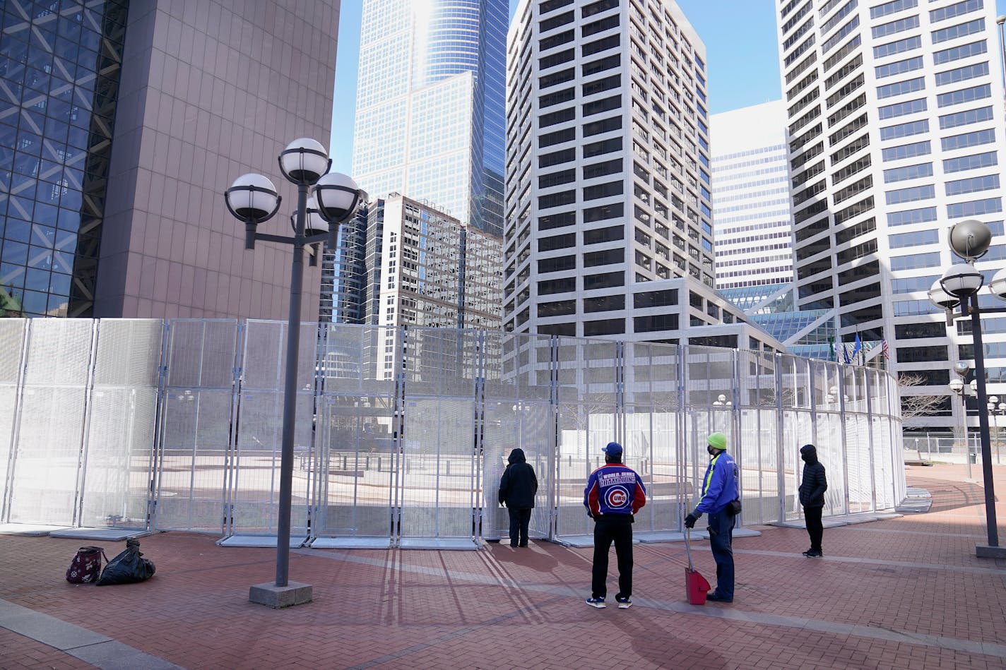 People wait to conduct business outside the Hennepin County Government Center with a law enforcement officer inside a fenced perimeter as preparations continue for the murder trial of former Minneapolis police officer Derek Chauvin which begins Monday and was seen near the Hennepin County Government Center Thursday, March 4, 2021 in Minneapolis. (David Joles/Star Tribune via AP)