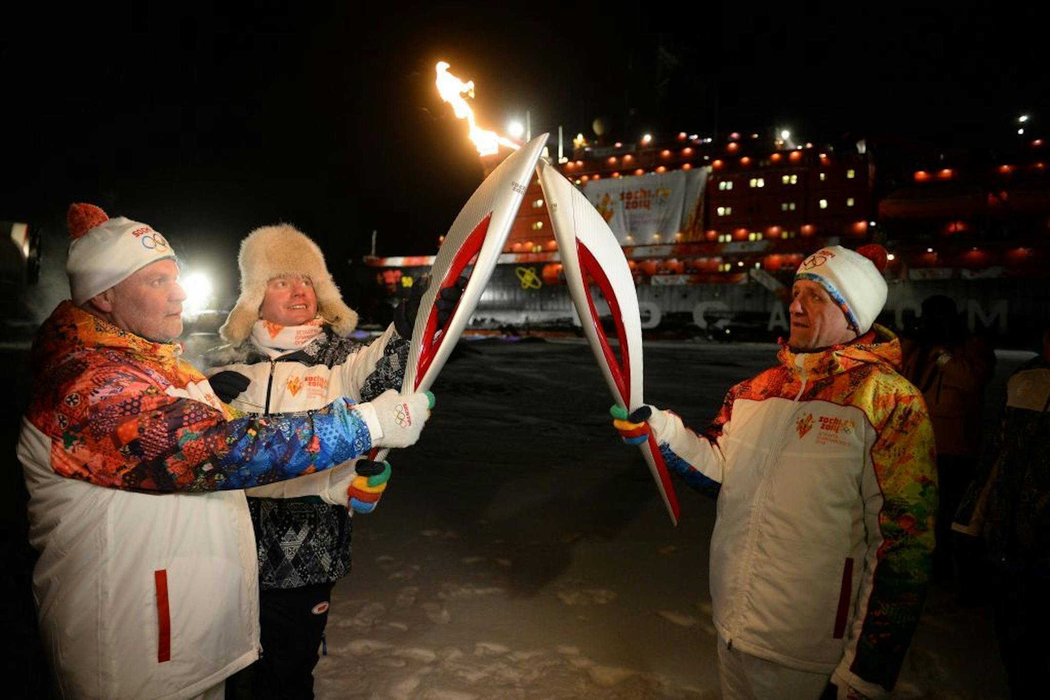 In this photo taken on Saturday, Oct. 19, 2013 and made available by olympictorch2014.com on Friday Oct 25, a group of torch bearers hold torches at the North Pole, Arctic Ocean. The nuclear-powered icebreaker 50 Let Pobedy (50 Years of the Victory) is in the background. For the first time in history the Olympic flame was brought to the North Pole, on board the ship as part of the torch relay to the 2014 Sochi Winter Games.