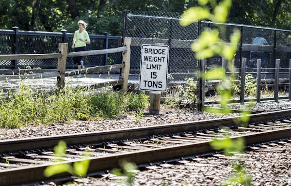 A runner crosses the bridge on the Kenilworth Trail that runs parallel to railroad tracks over the channel that runs between Lake of the Isles and Ced