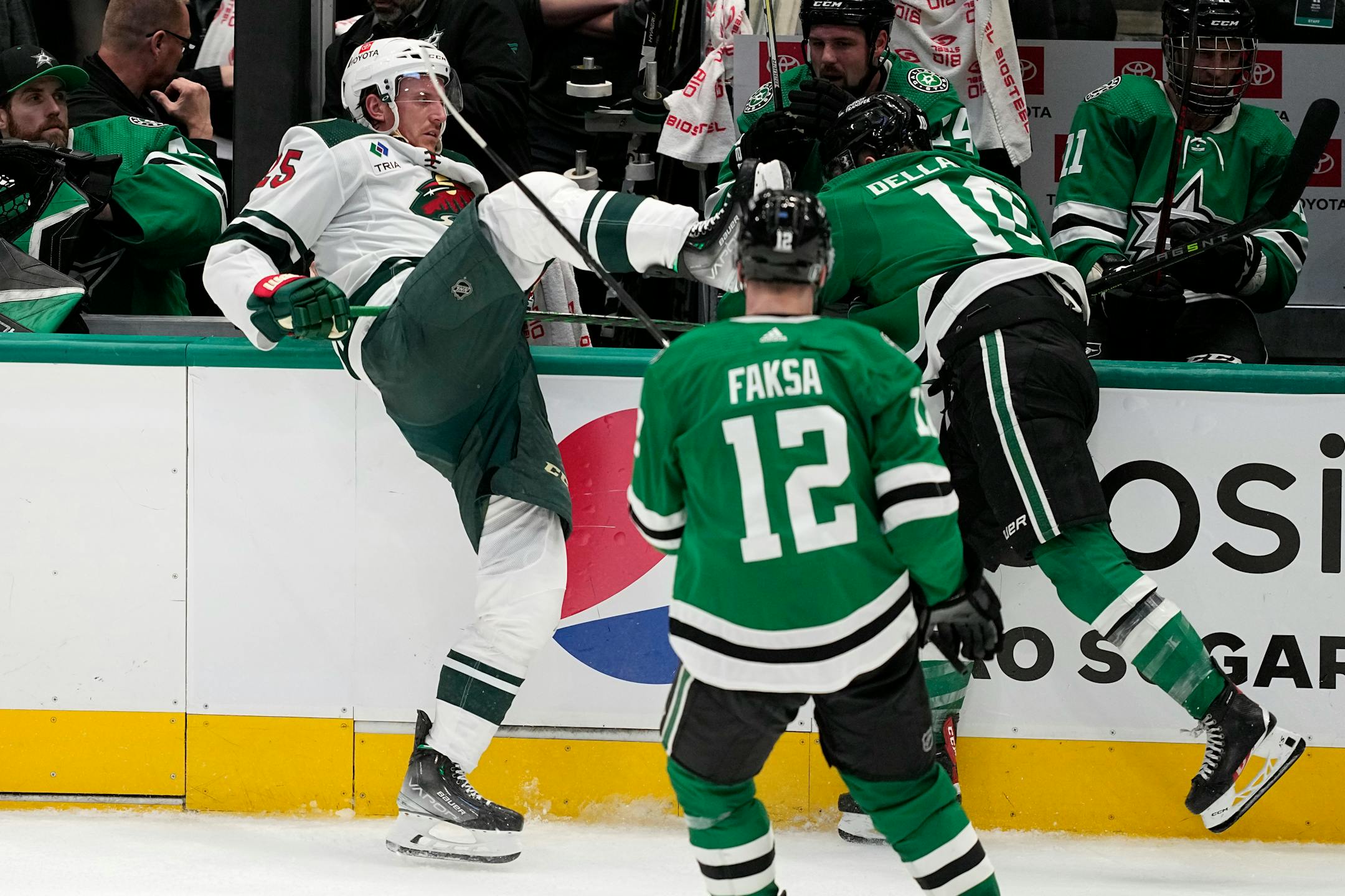 Minnesota Wild's Jonas Brodin (25) is knocked into the boards by Dallas Stars' Ty Dellandrea (10) as Radek Faksa (12) looks on in the third period of Game 1.