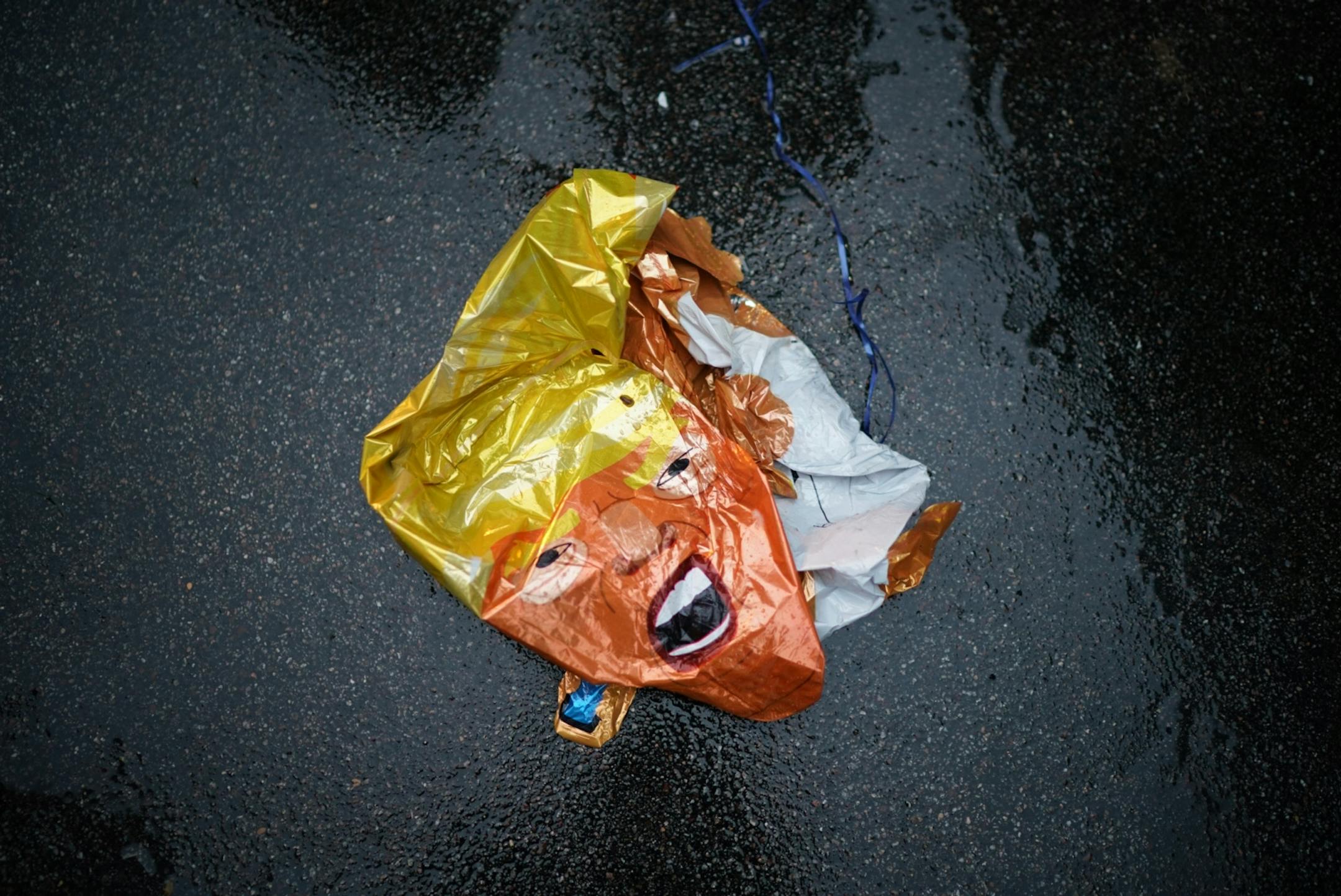 Supporters of and protesters against President Trump interact outside Target Center. Here, a deflated balloon of the president sits on the ground.
