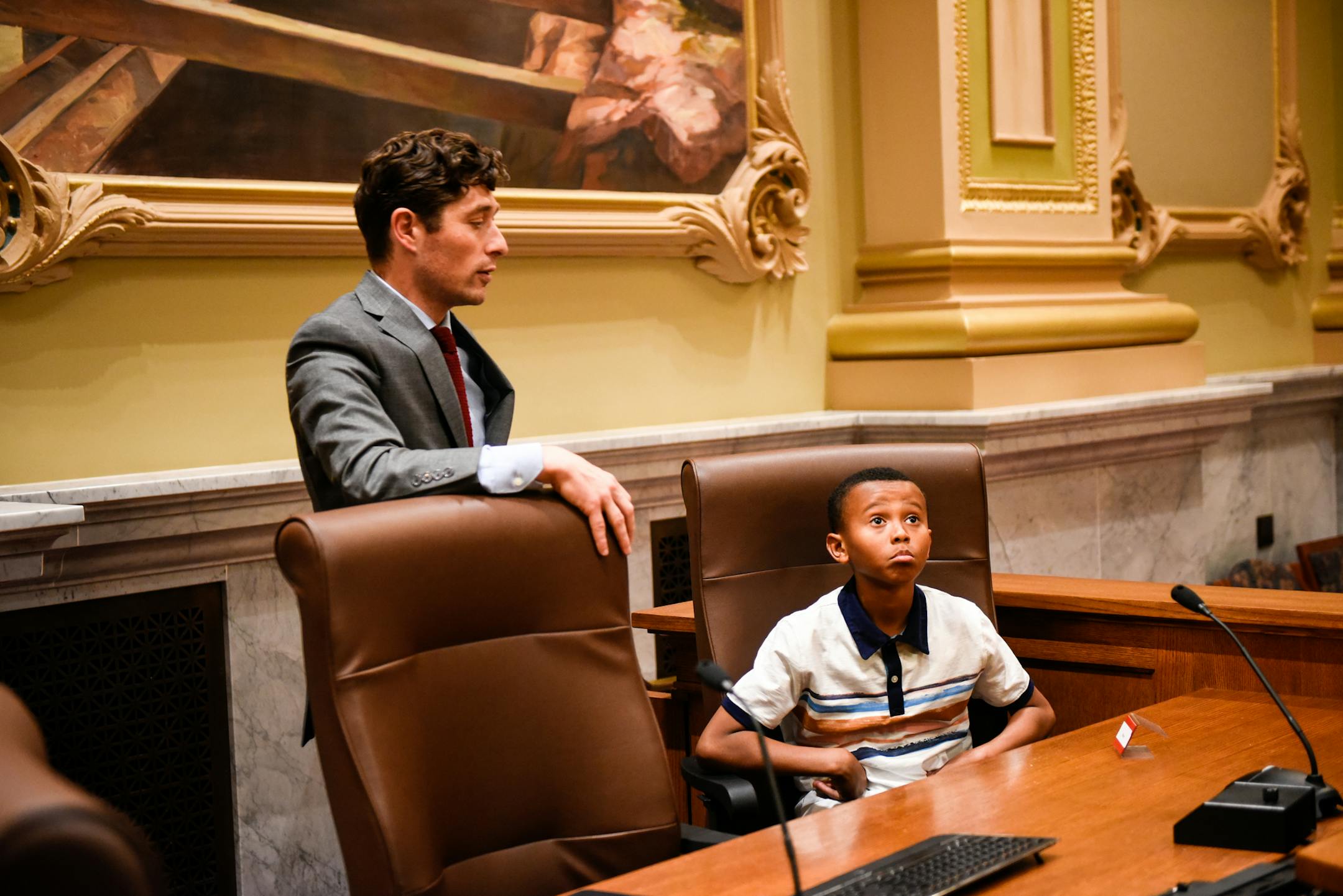 10-year old Jayden Goldsboro sat in Minneapolis Mayor Jacob Frey's chair in the city council chambers during a tour Wednesday. ] AARON LAVINSKY ï aaron.lavinsky@startribune.com Minneapolis Mayor Jacob Frey held an unveiling ceremony Wednesday afternoon to celebrate the art of 10-year old Jayden Goldsboro, whose work was hung next to the entrance of Mayor Frey's office. Frey met Jayden earlier this year and purchased his painting at an Art is My Weapon exhibition. The Art is My Weapon progra