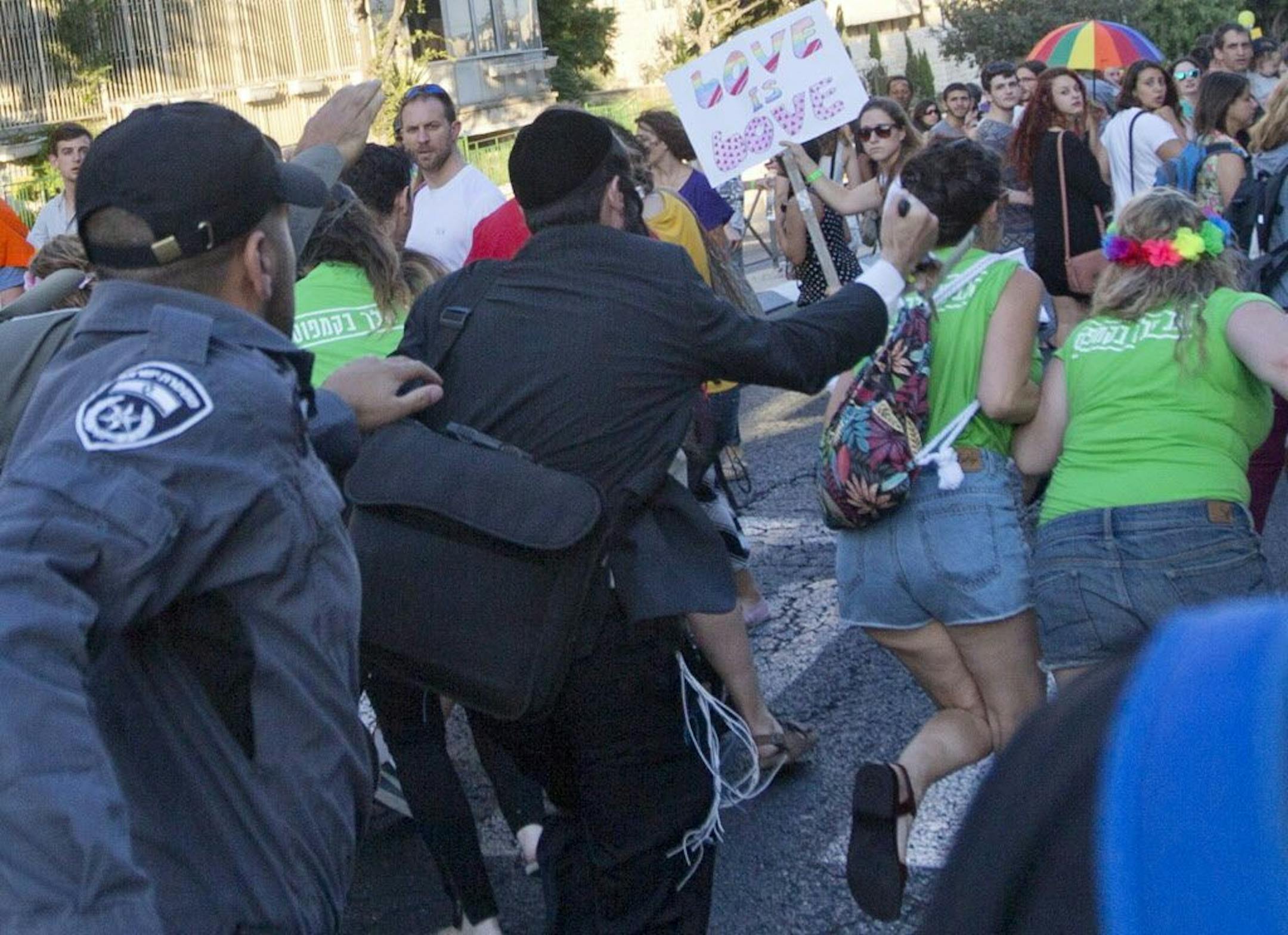 An ultra-Orthodox Jew stabs a woman in the back with a knife during a Gay Pride parade Thursday, July 30, 2015 in central Jerusalem. Israeli police said several people were stabbed.
